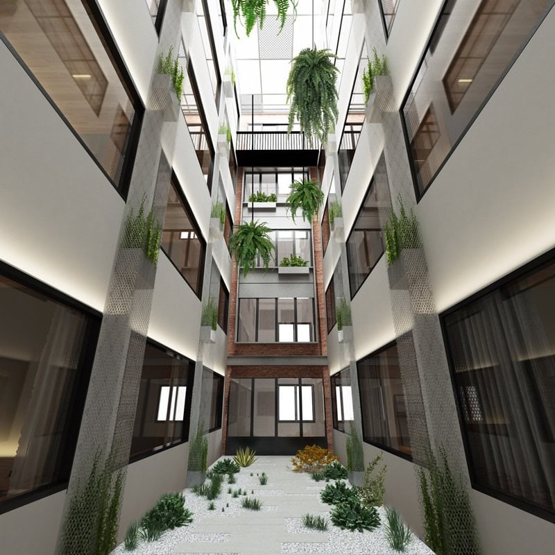 Modern indoor atrium with large windows, several floors, hanging and potted plants, and natural light coming from a glass ceiling above. The ground level features green plants and decorative stones.