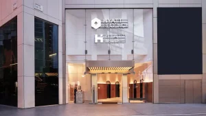 The entrance of a modern building with large glass doors and windows, displaying illuminated signs for Hyatt Regency and Hyatt House above the doorway.