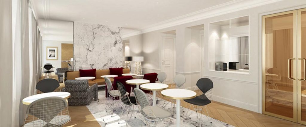 A modern lounge with round white tables, wireframe chairs, sofas with red cushions, a marble accent wall, wood flooring, and large windows allowing natural light into the bright, elegant space.