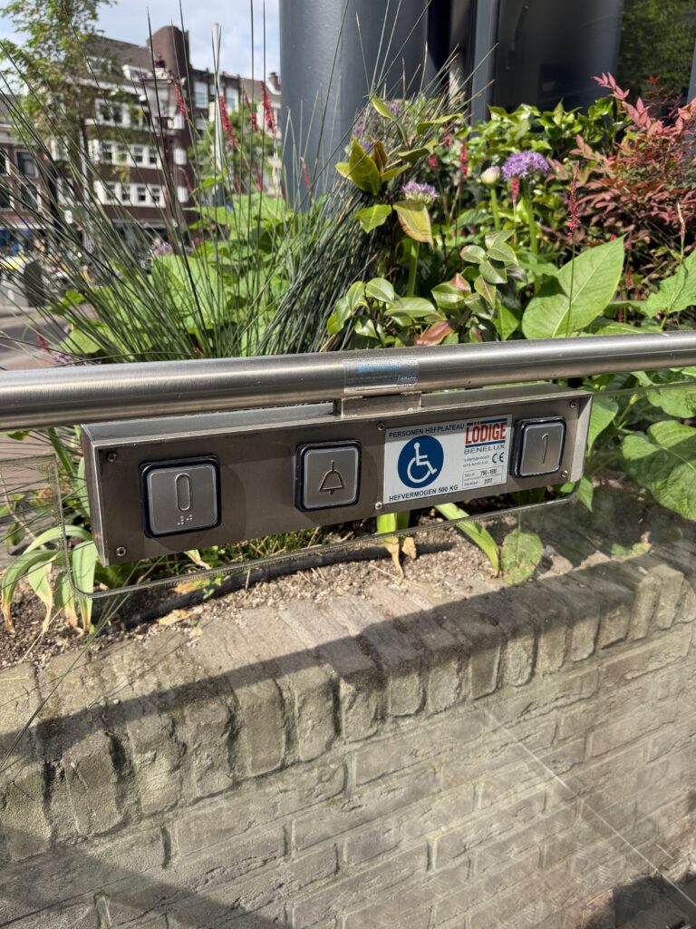 Platform lift control panel with braille-marked floor buttons and alarm button.