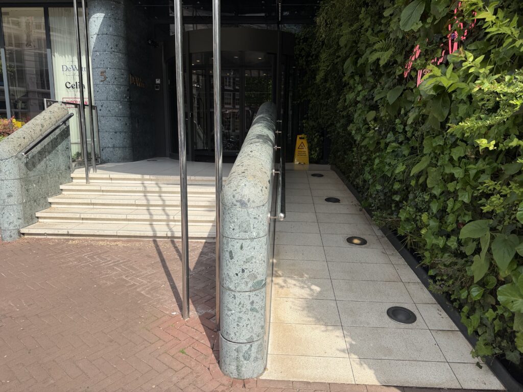 Hotel entrance steps with stainless steel handrails on both sides, platform lift adjacent.