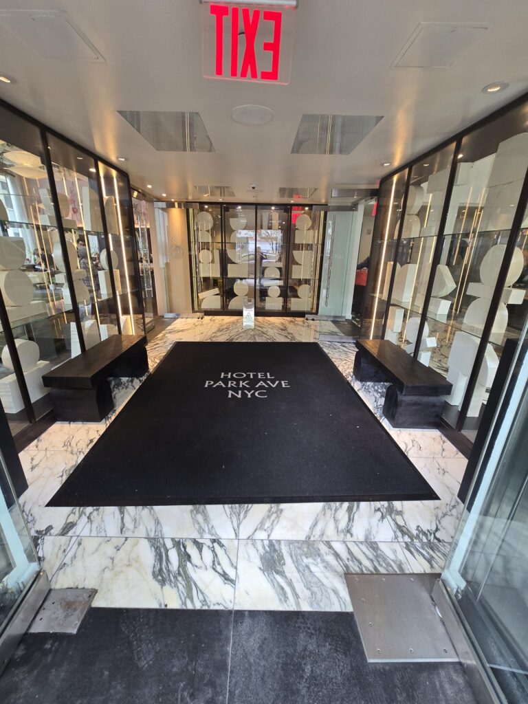 Entrance vestibule at Hotel Park Ave NYC. Marble floor, logo entrance mat, glass doors, level threshold from street to lobby.