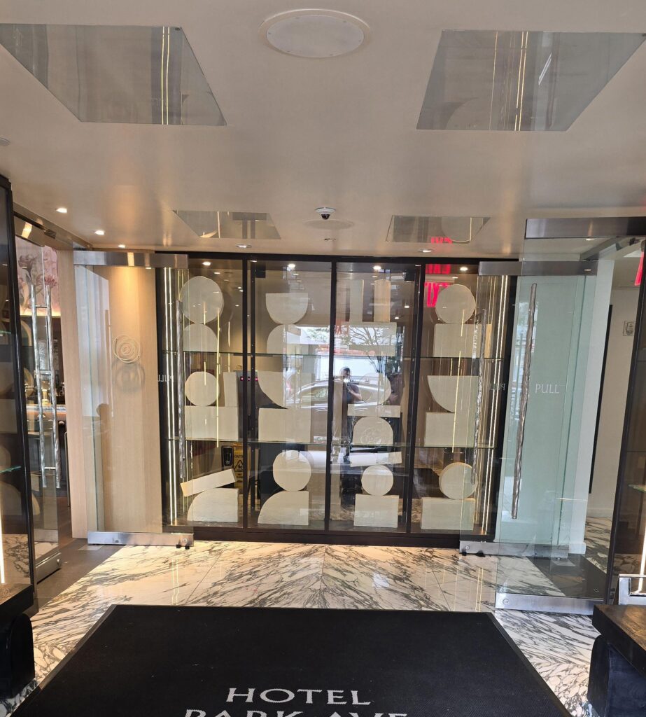 Park Av and should read Entrance vestibule at Hotel Park Ave NYC. Glazed doors with circular decorative motifs, marble floor, “Hotel Park Ave” logo entrance mat, level threshold from the street.