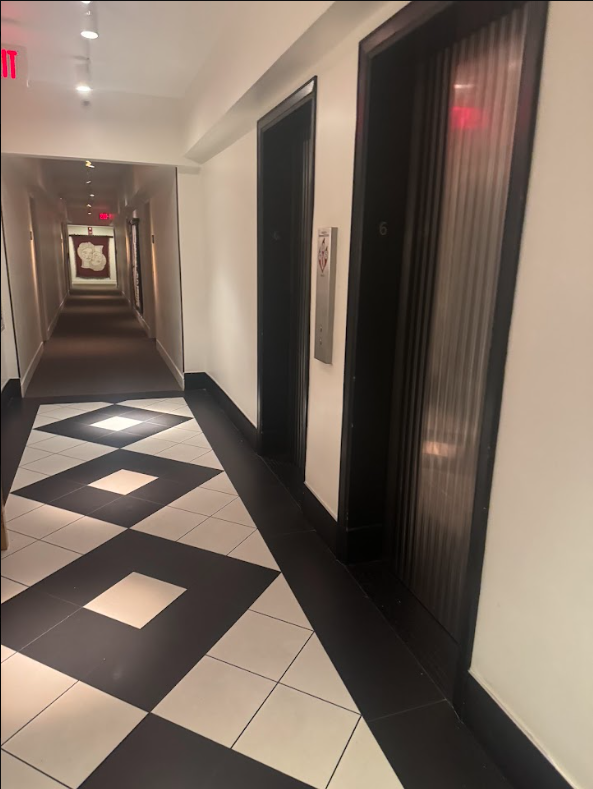 Guest-floor corridor at Lyle Washington DC. Patterned tile flooring by the lift lobby meeting corridor carpet, lifts to one side, corridor running the length of the floor.